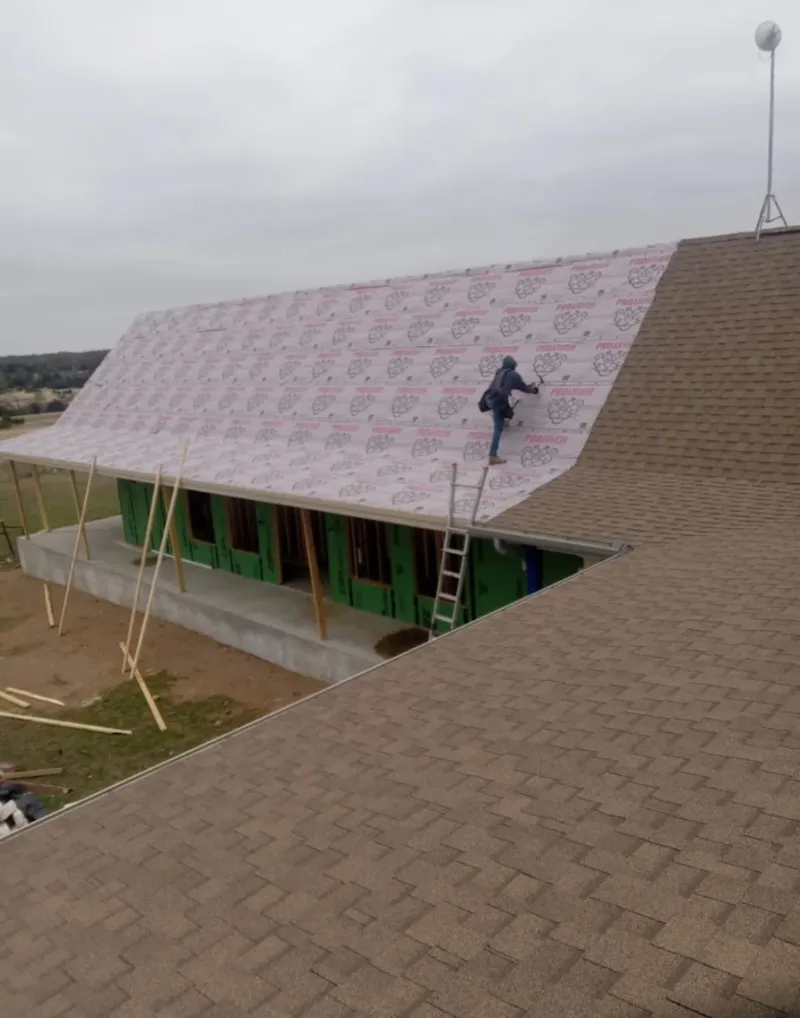 Worker preparing underlayment for a metal roof installation in Woodbury